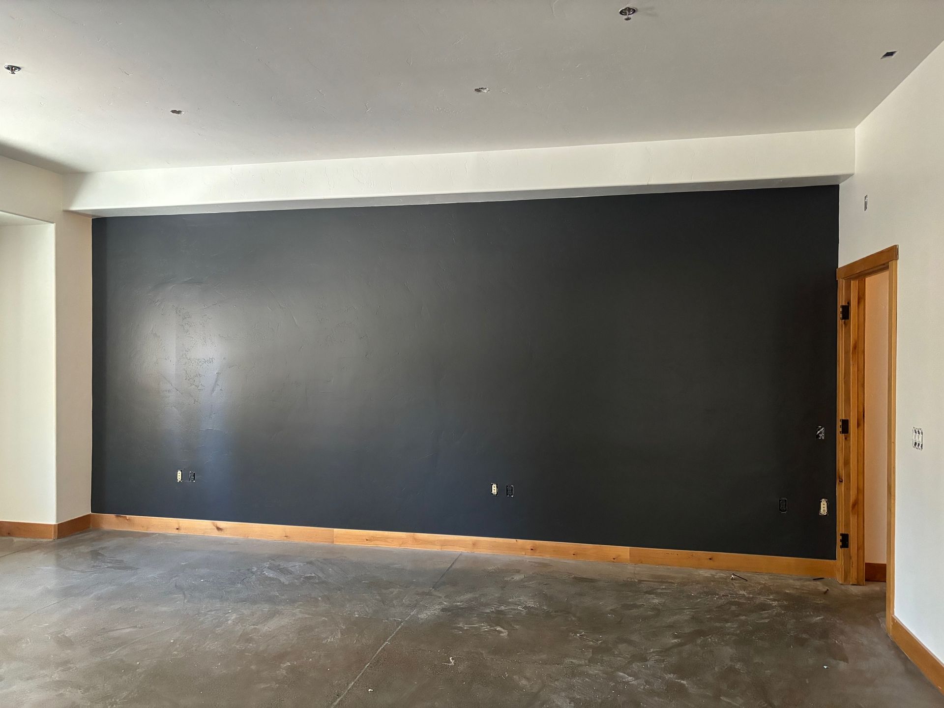 A finished charcoal accent wall with cedar baseboard and trim