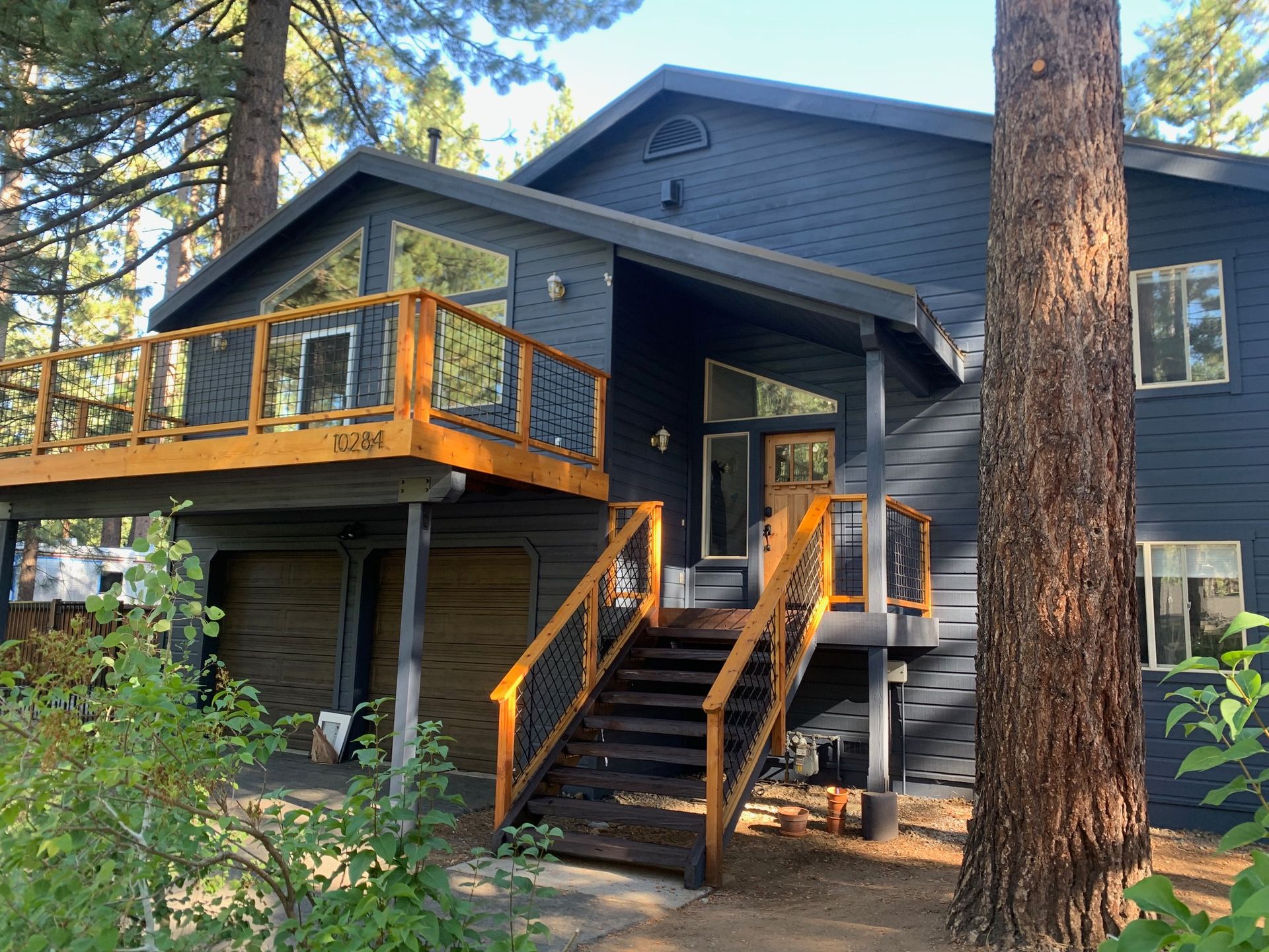 A Truckee home finished in deep charcoal with a cedar deck and stairs, under ponderosa pines at golden hour
